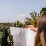 Imagen de una mujer buscando en un mapa los mejores sitios para pasear en Málaga.