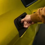 Persona abriendo el depósito de un coche amarillo Yellow Car en una gasolinera para repostar antes de una ruta por Málaga