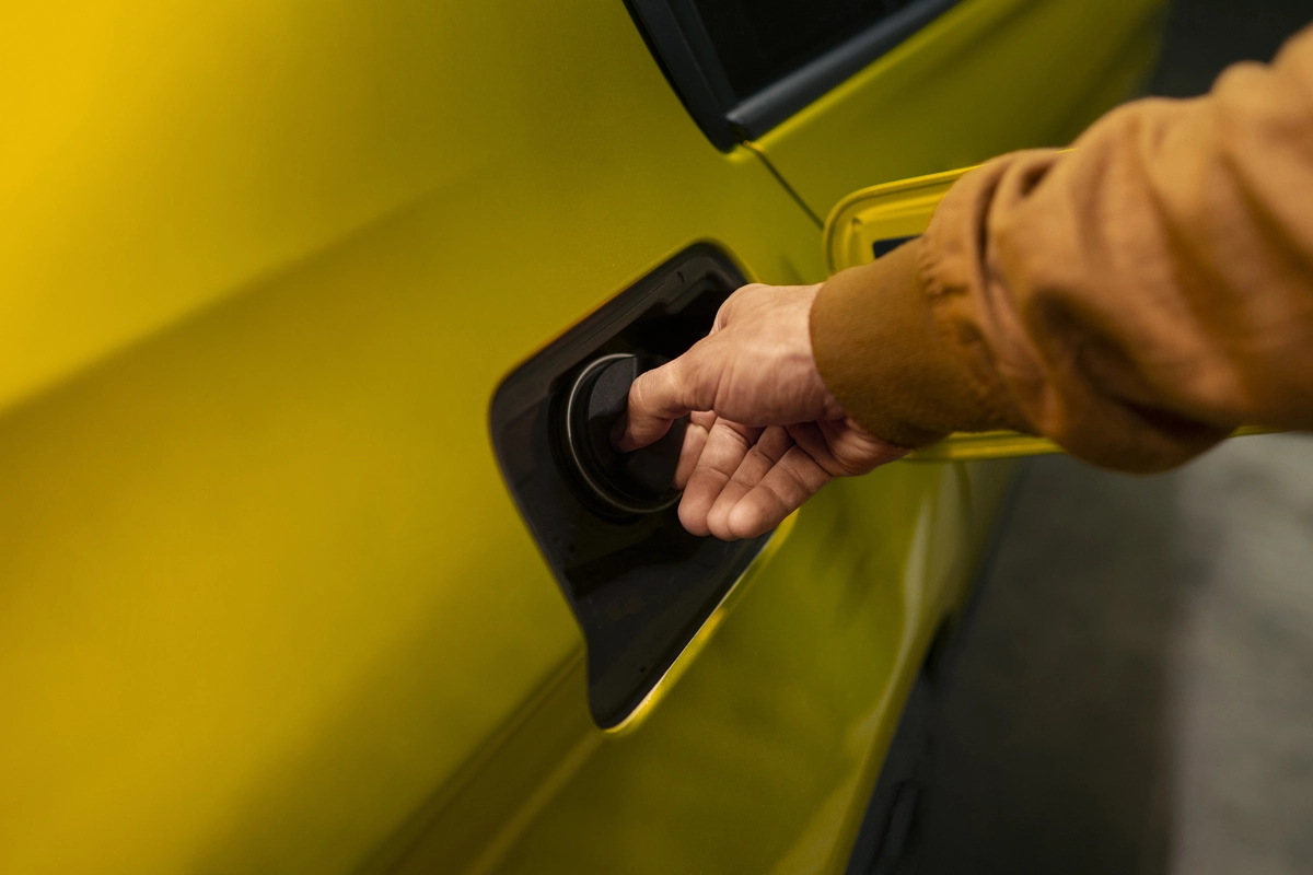 Persona abriendo el depósito de un coche amarillo Yellow Car en una gasolinera para repostar antes de una ruta por Málaga